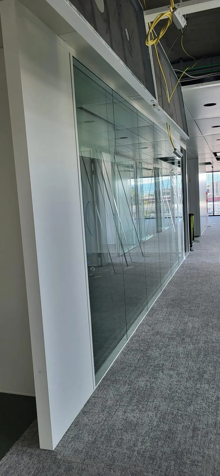 Ganzglas-Trennwand mit grünlich schimmernder Glaskante auf Teppichboden
