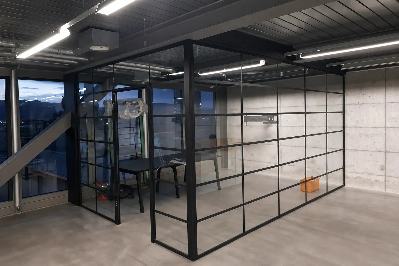 Loft-Glaswand mit schwarzem Stahl-Sprossenraster vor Sichtbeton