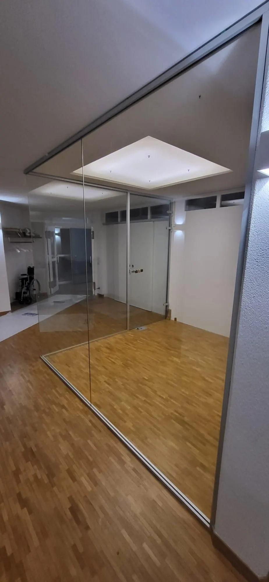 Ganzglas-Trennwand auf Parkettboden, Hochformataufnahme