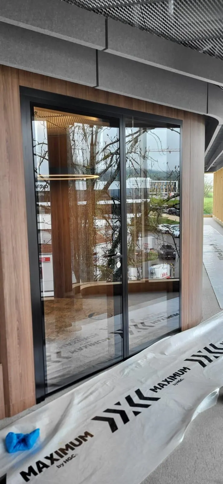 Gebogene Meetingbox mit Holzverkleidung und Glas, Montageschutz am Boden