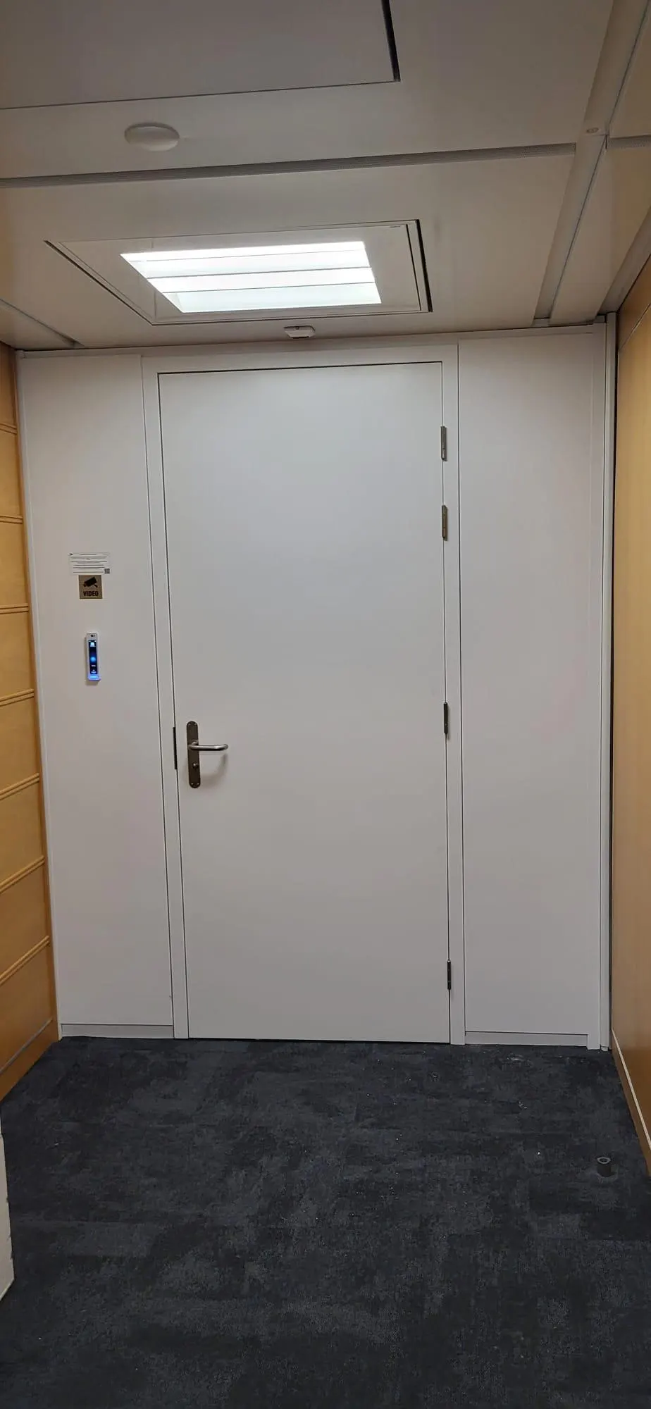 Weisse Vollwand-Tür in einer Systemtrennwand mit Holzdekor-Zarge